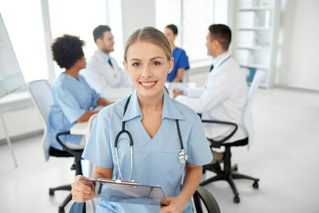 Fototapeta premium happy doctor with clipboard over group of medics