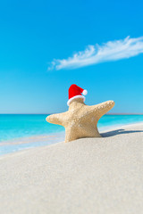 Fototapeta na wymiar Sea-star in red santa hat at tropical sea beach.