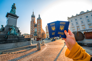 Fototapeta Female hands holding Ukrainian abroad passports on the Krakow city center background obraz