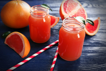 Grapefruit juice in bottles and fresh fruits on dark blue wooden background
