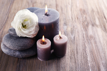 Aroma candle with pebbles and flower  on wooden background