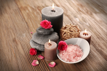 Obraz na płótnie Canvas Relax set which include aroma candles, flowers, petals and pebbles on wooden background