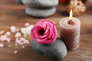 Beautiful composition of aroma candle with pebbles and flower  on wooden background