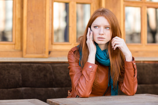 Worried concerned woman talking on cellphone in outdoor cafe