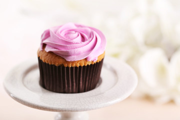 Tasty cupcake on stand, on light background