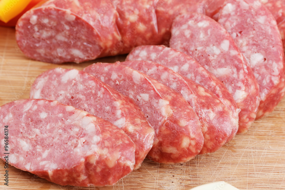 Wall mural Sliced sausages with fat on a wooden board