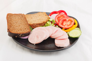 Sliced ham with dark bread on a plate
