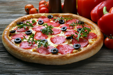 Tasty pizza with salami and red vegetables on wooden background, close up