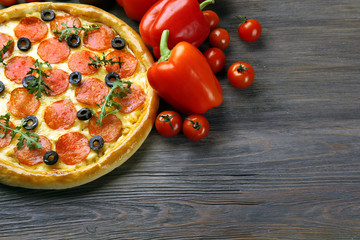 Tasty pizza with salami and red vegetables on wooden background, copy space