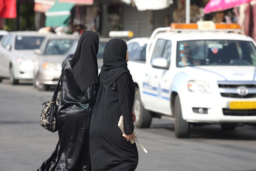 Fototapeta premium Muslim woman in traditional clothing walking down the street