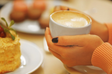 Woman holding cup of coffee in cafe, closeup