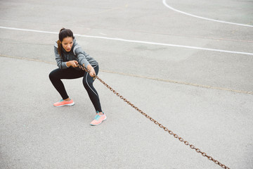 Fototapeta premium Fitness woman pulling chain for strength workout
