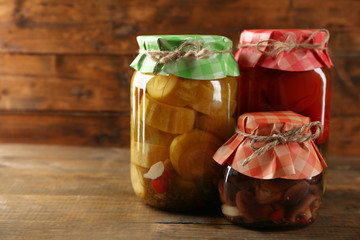 Jars with pickled vegetables on wooden background