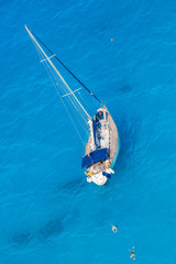 White luxury yacht against azure sea with swimming people