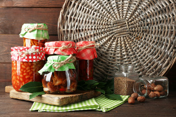 Jars with pickled vegetables and mushrooms on wooden background