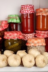 Jars with pickled vegetables and beans on wooden shelf