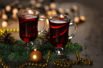 Mulled wine with spices and Christmas tree on wooden background