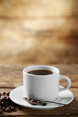 Cup of coffee and coffee grains on wooden background
