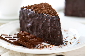 Chocolate cake with chocolate cream on plate, on light background