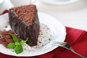 Chocolate cake with chocolate cream on plate, on light background