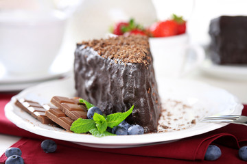 Chocolate cake with chocolate cream on plate, on light background