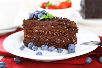 Chocolate cake with chocolate cream and fresh berries on plate, on wooden table, on light background