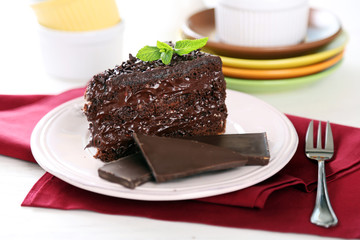 Chocolate cake with chocolate cream on plate, on light background