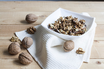 Walnuts in a old white bowl on a wooden background