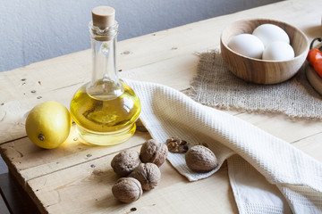 Food ingredients. Oil, eggs, garlic, limon and walnuts on wooden table. Wooden board and napkin.