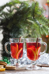 Tea with lemon, tangerines, cookies and nuts in Christmas decor with Christmas tree, nuts and apples on colorful background bokeh