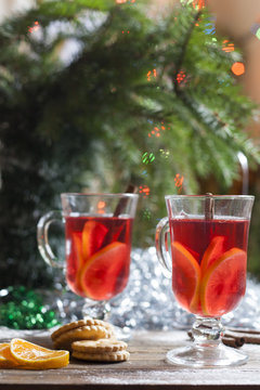 Tea with lemon, tangerines, cookies and nuts in Christmas decor with Christmas tree, nuts and apples on colorful background bokeh