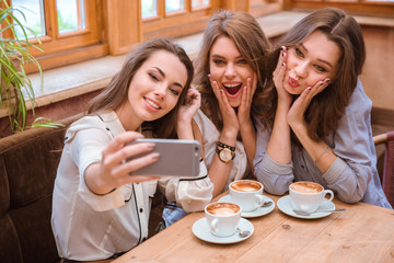 Three women making selfie photo in cafe