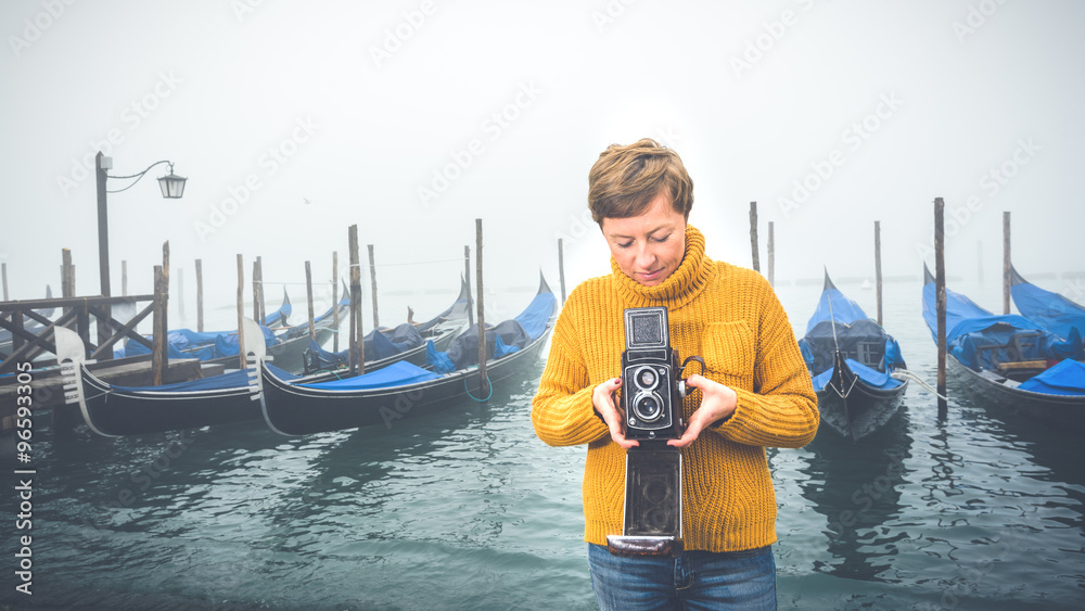 Wall mural Beautiful young woman photographing gondolas in Venice, Italy