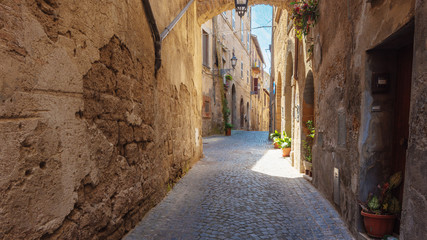 Italian streets with arches on a sunny day and long shadows