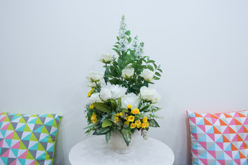 Artificial flowers bouquet in vase on the table and couple pillo