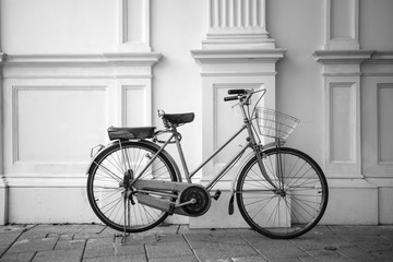 Fototapeta na wymiar B&W vintage bicycle parked next to a white wall.