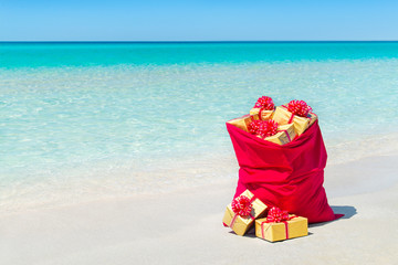 Christmas sack full of wrapped gift boxes at tropical beach