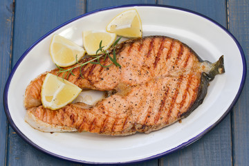 grilled salmon with lemon on dish on blue wooden background