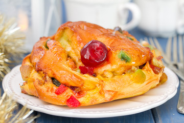 Christmas cake on white dish on blue wooden background with cups of coffee