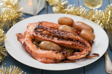 boiled octopus with potato on white plate on blue background