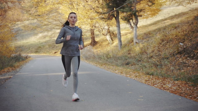Female athlete running on forest road.