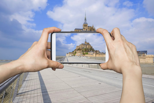 Girl taking pictures on mobile smart phone in Mont Saint-Michel,