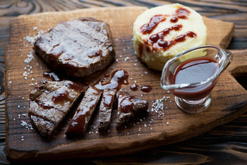 Grilled marbled beef steaks with potato puree and sauce, closeup