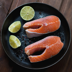 Closeup of a frying pan with raw fresh trout steaks, studio shot