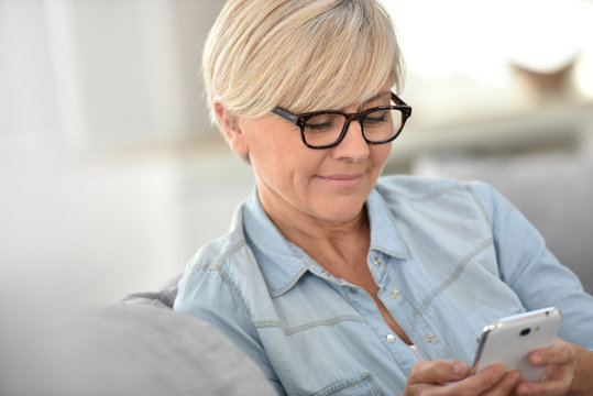 Senior woman with eyeglasses sending text message