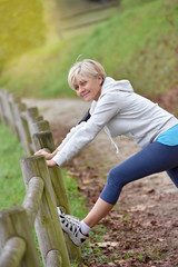 Senior woman stretching after exercising in natural landscape