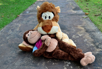 Monkey and lion doll hugging in garden
