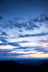 panoramic view of a series of hills of the Valsesia (Piedmont, Italy) at sunset with blue and pink clouds.