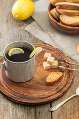 metal cup of tea, brown sugar, crackers and lemon
