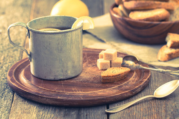 Fototapeta na wymiar metal cup of tea, brown sugar, crackers and lemon